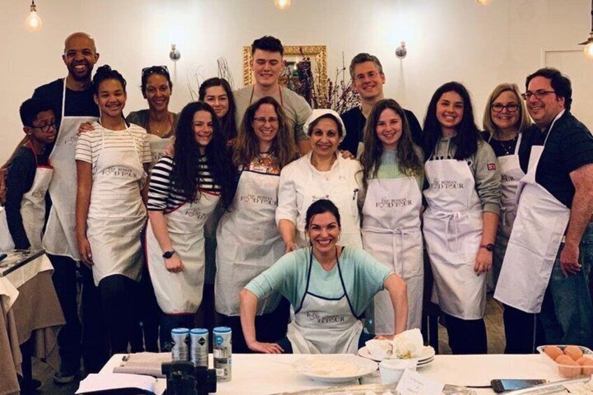 A group of people in aprons, some standing, some seated, with a table in front of them. 5