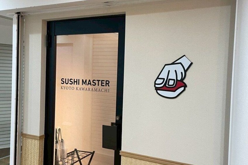 Ingresso di un ristorante sushi con un cartello che riporta 'SUSHI MASTER KYOTO KAWARAMACHI' e un logo stilizzato a forma di mano. 4