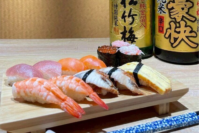 Variedad de sushi sobre una tabla de madera, con dos botellas de salsa de soja al fondo. 3