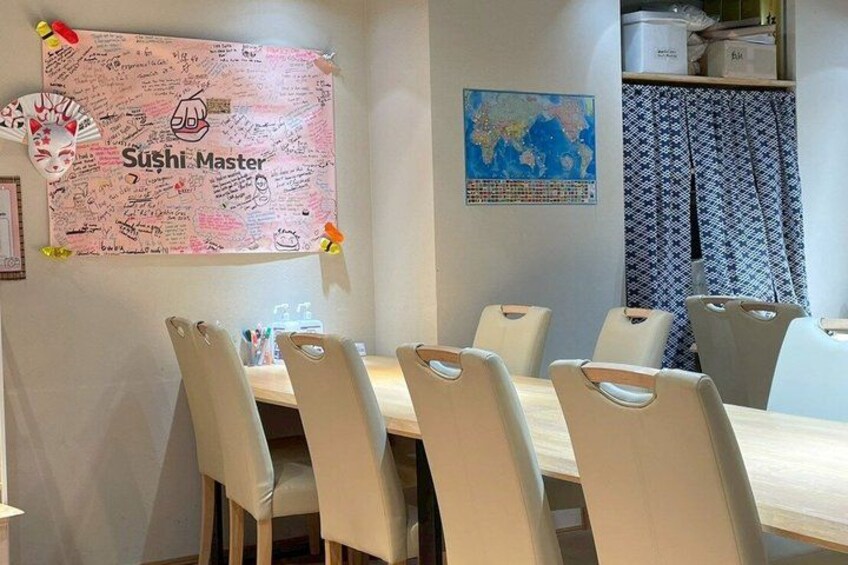 Un'area pranzo con tavolo e sedie, una parete con un poster 'Sushi Master' e una mappa del mondo. 2