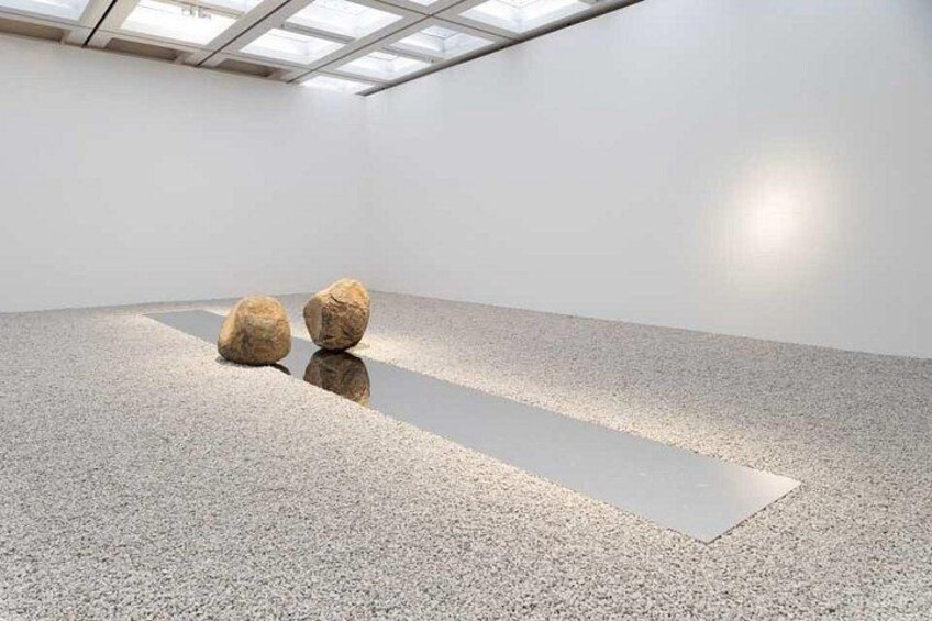 Una galería de arte interior con piso pulido y dos rocas grandes. 3