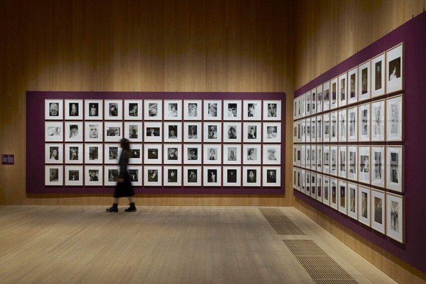 Una galería de arte con suelos y paredes de madera, que exhibe numerosas fotografías en blanco y negro enmarcadas. 5