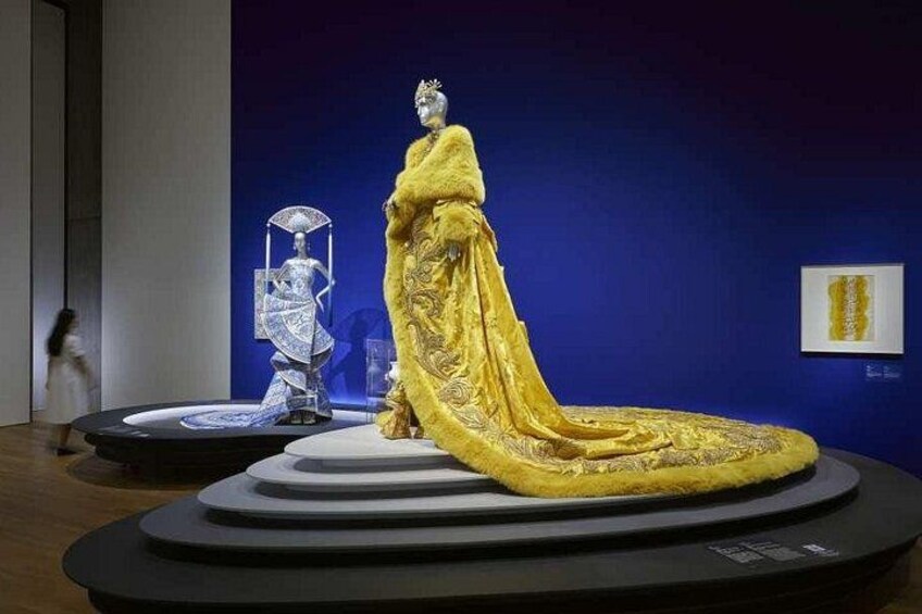 Un maniquí con un vestido dorado sobre una plataforma con fondo azul. 2