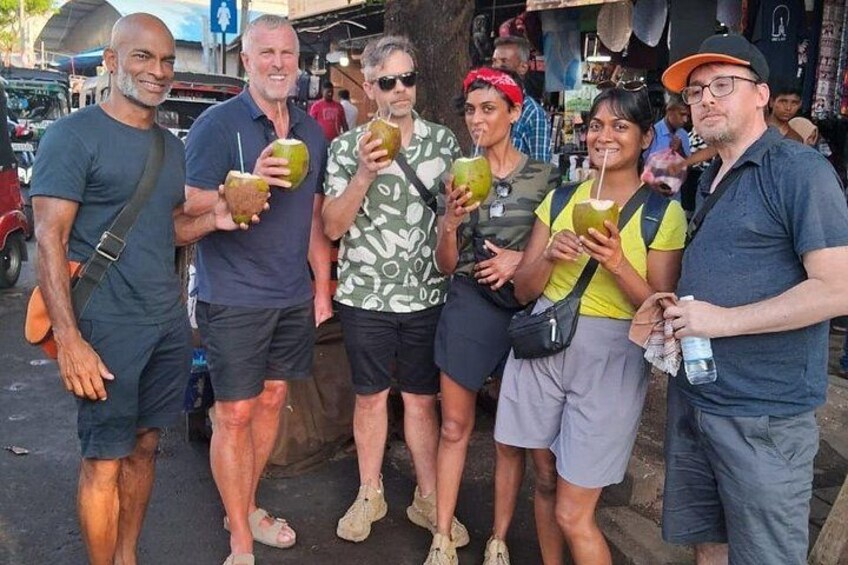 A group of people standing outdoors, some holding drinks. 3