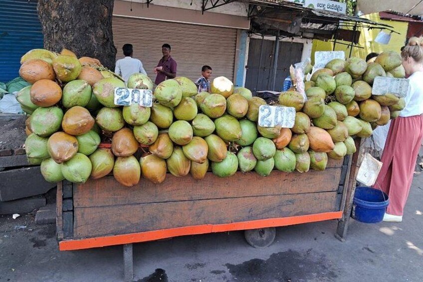 A cart loaded with coconuts, a sign indicating the price, and a person standing nearby. 2