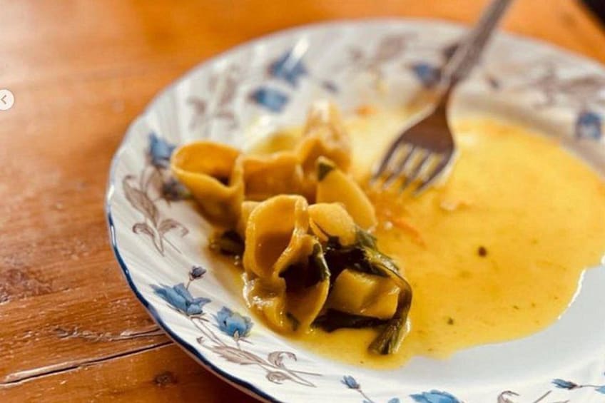 A plate of pasta with a yellow sauce and a fork on a wooden table. 3