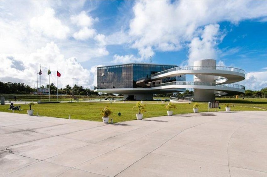 A modern building with a circular design, surrounded by a well-maintained lawn and potted plants. 3