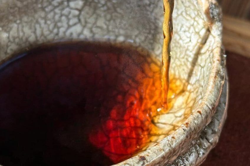 A close-up of a textured bowl with a dark liquid, possibly tea or coffee, being poured into it. 2