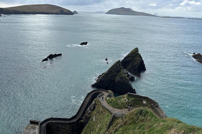 A coastal landscape with a sea wall, rocky outcrops, and a distant island. 3