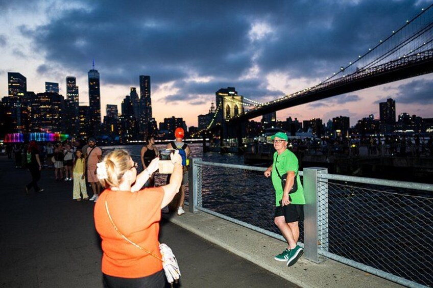 Une personne prend une photo d’un pont, avec la silhouette d’une ville en arrière-plan. 3