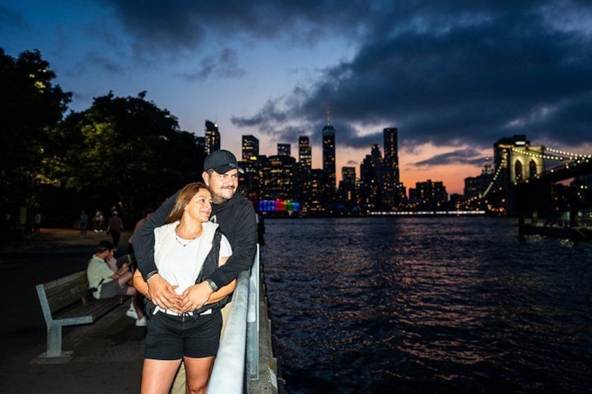 A couple standing by a waterfront with a city skyline in the background. 2