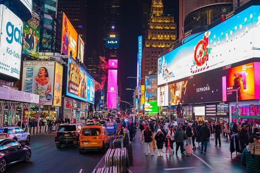Une rue animée d'une ville, de nuit, avec des panneaux publicitaires illuminés et une foule de personnes. 3