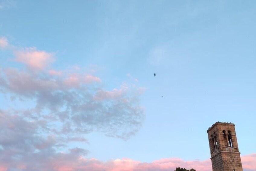A clear sky with a few clouds and a tall tower with a bell. 5