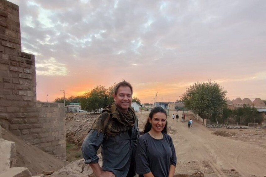 A man and a woman standing on a dirt road with a sunset in the background. 4