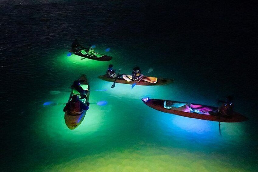 Four kayaks on a body of water at night. 1