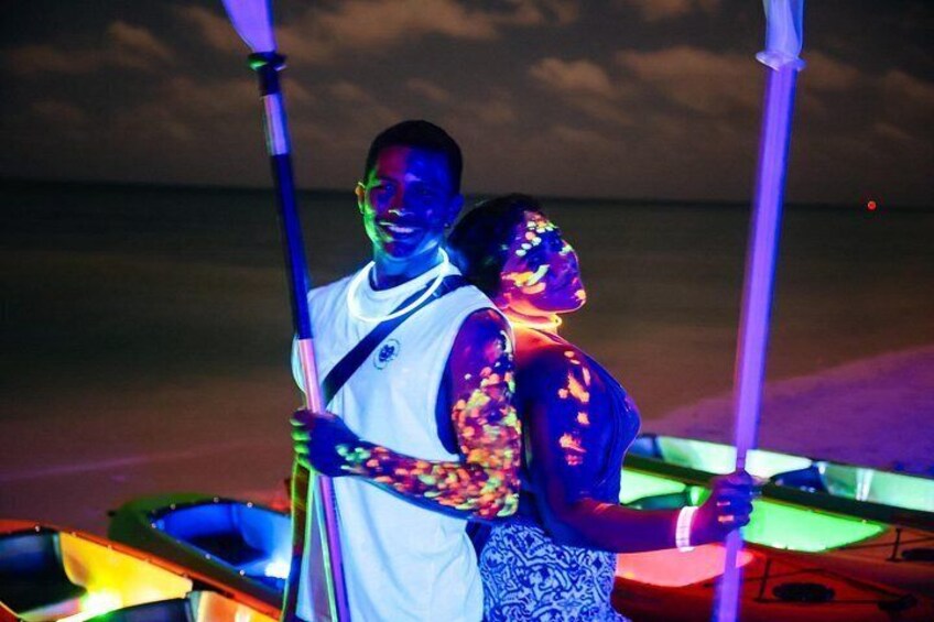 A couple embracing on a boat at night with colorful lights. 3
