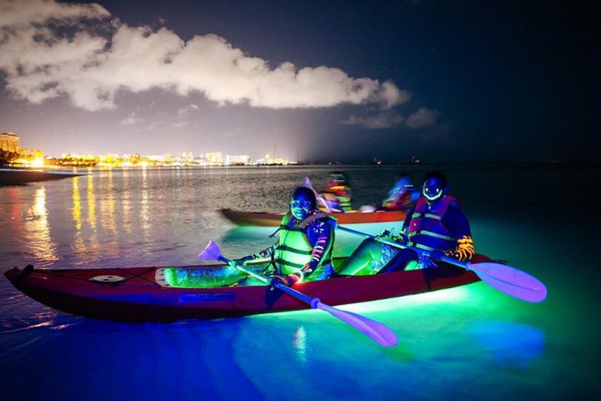 Two kayaks with illuminated interiors on a calm body of water at night. 2