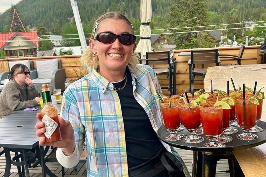 Una persona sostiene una botella de salsa Basco, con varios vasos de Bloody Mary sobre una mesa. 2