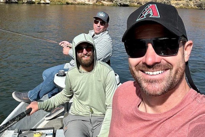 Two people on a boat, one wearing a cap with a logo, and another in a light green shirt. 1