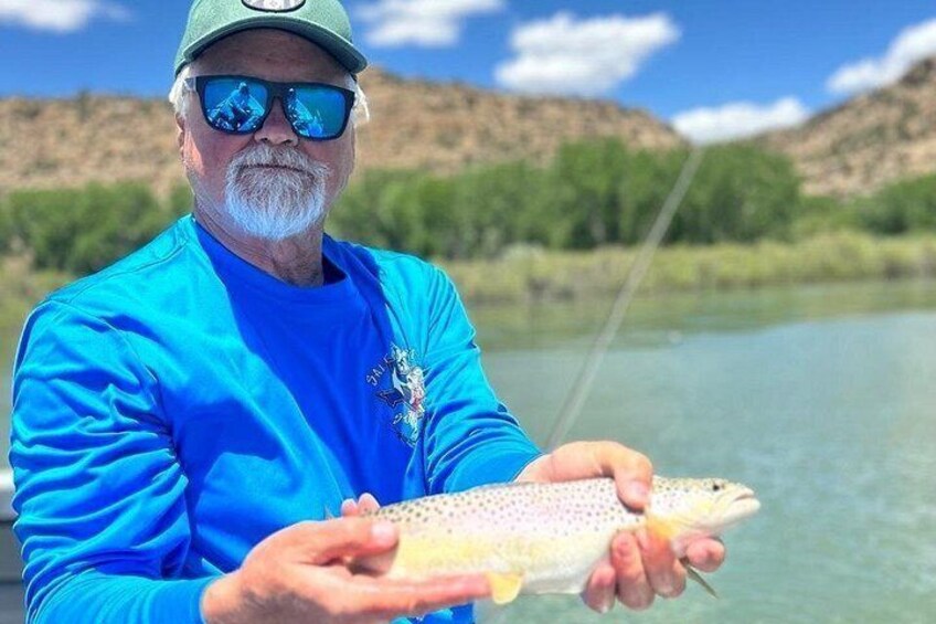 A person holding a fish by a river. 5