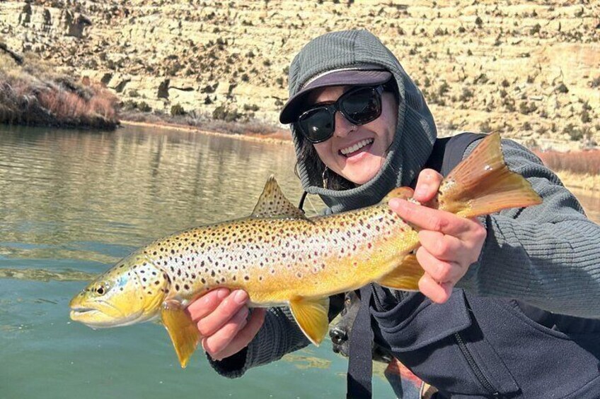 A person holding a trout by a river. 4