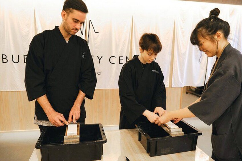 Three people in black medical attire handling a box with a white label. 2