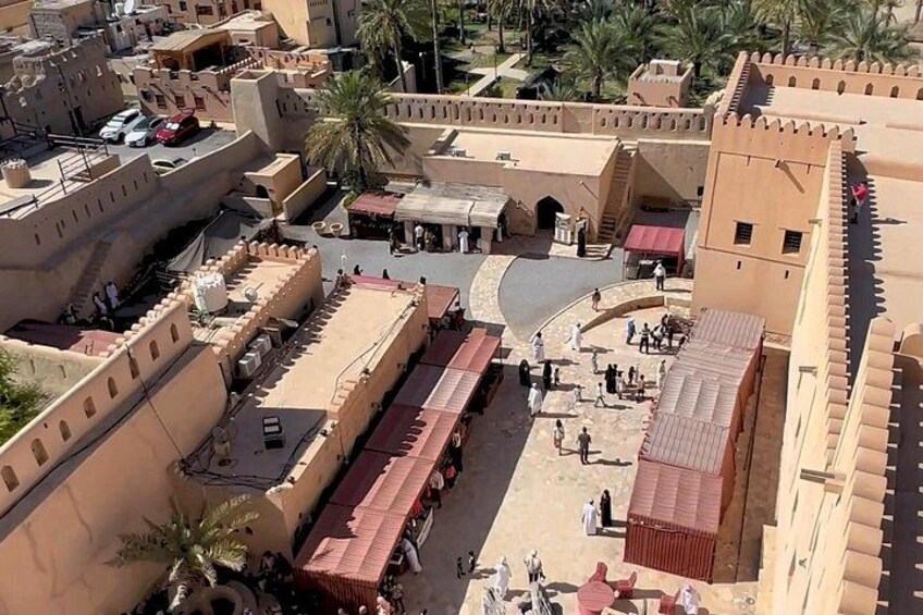 A fortified historical site with a central courtyard, surrounding walls, and palm trees. 4