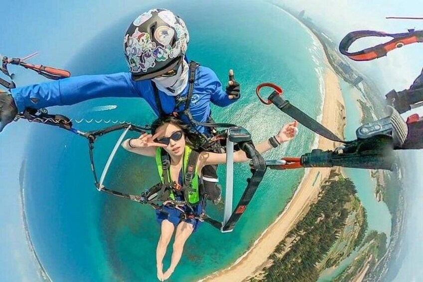 A person skydiving with a parachute over a coastal landscape. 3