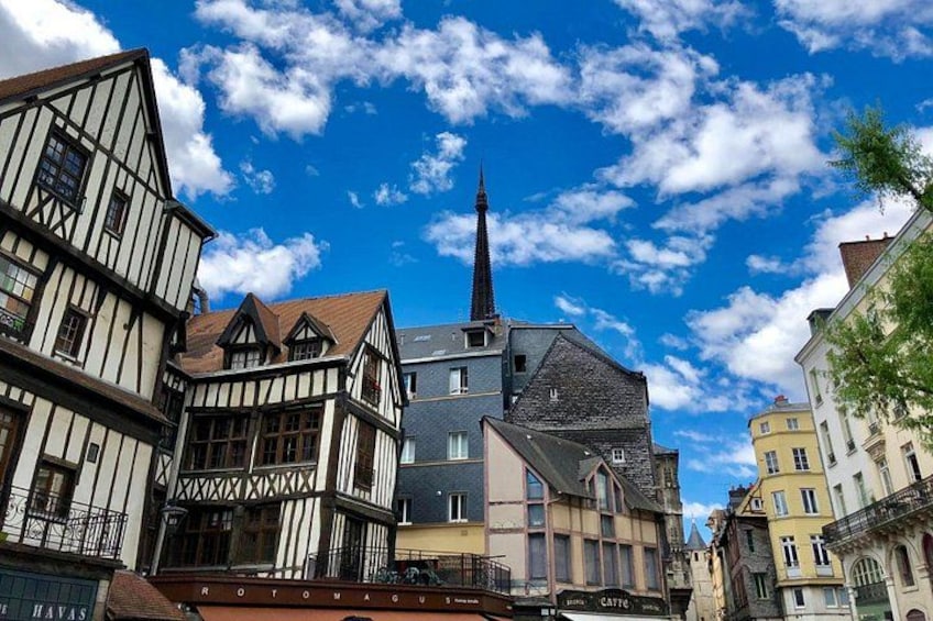 Un pueblo europeo con edificios de entramado de madera, una aguja de iglesia y un cielo azul despejado. 5