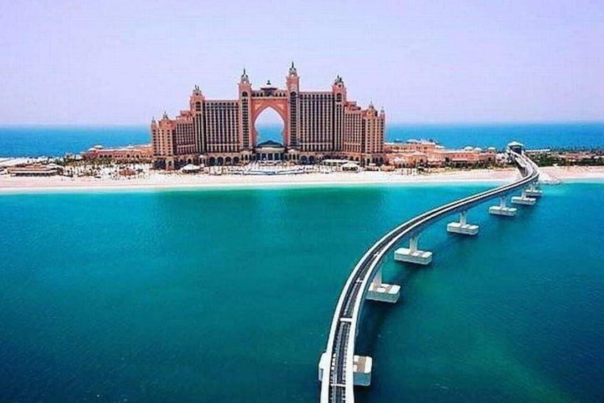 Un grand hôtel doté d’une entrée en forme d’arc remarquable, d’une longue jetée s’avançant dans l’eau et donnant sur une mer d’un bleu limpide. 4
