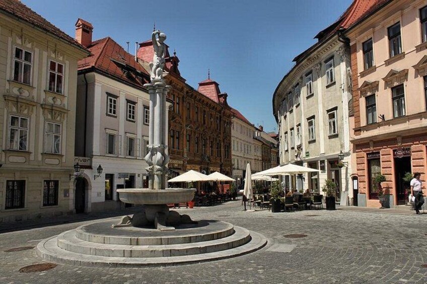 A historic square with a central fountain, surrounding buildings, and outdoor seating. 2
