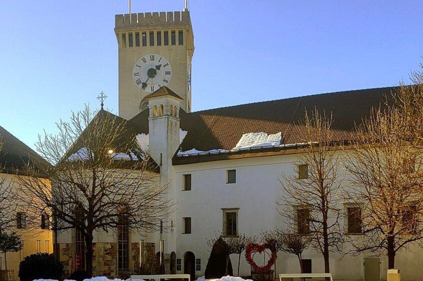 Ein Gebäude mit einem Glockenturm, umgeben von kahlen Bäumen und verschneitem Boden. 2