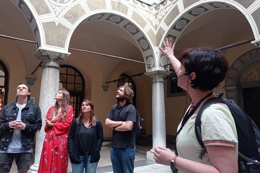Eine Gruppe von Menschen steht in einem architektonischen Innenhof mit Bögen und Säulen. 4
