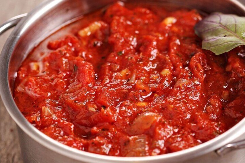 A pot of red sauce with herbs and a leaf garnish. 5