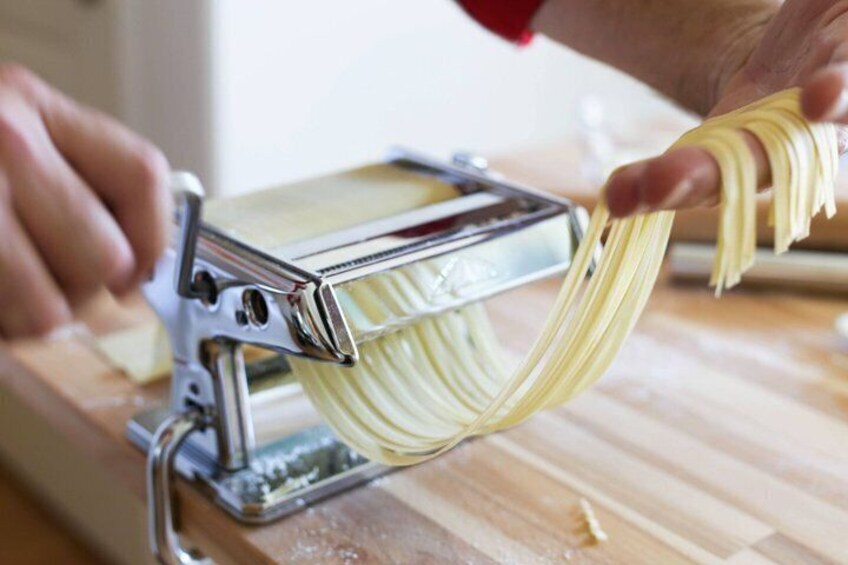 A person using a pasta machine to make pasta. 3
