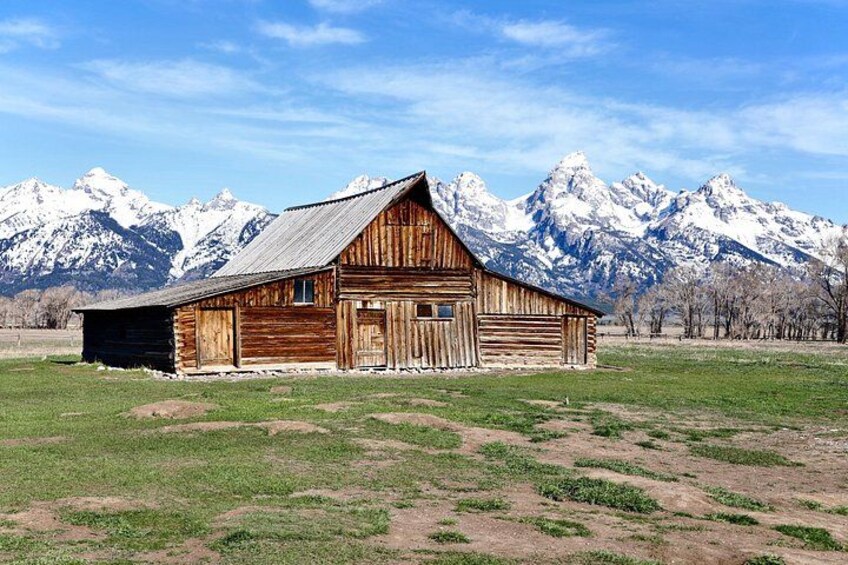 A rustic wooden barn with a snow-capped mountain range in the background. 1