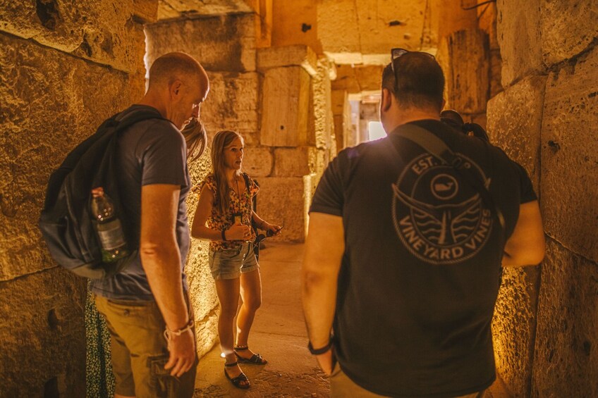 A group of people in a stone-walled corridor. 1