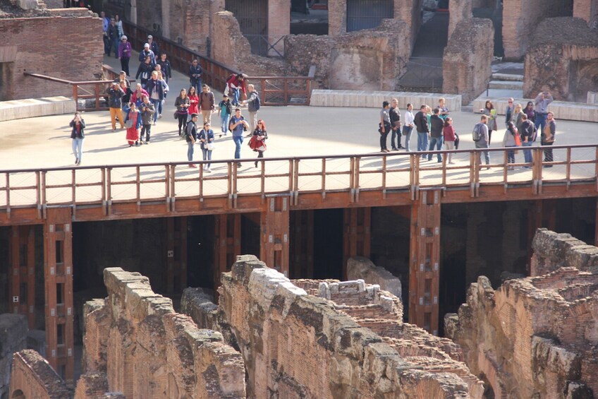 A group of people walking on a bridge over ancient ruins. 5