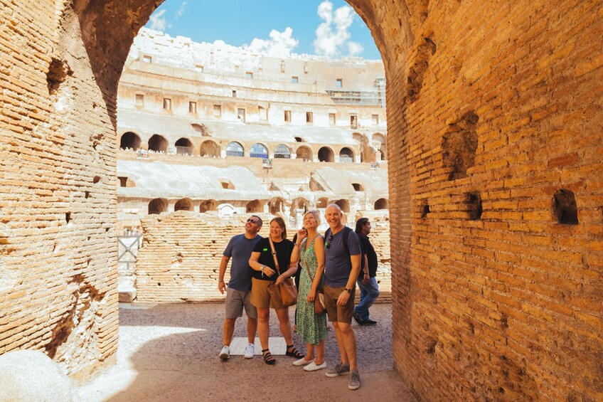 A group of tourists standing in an ancient amphitheater with brick arches and tiered seating. 3