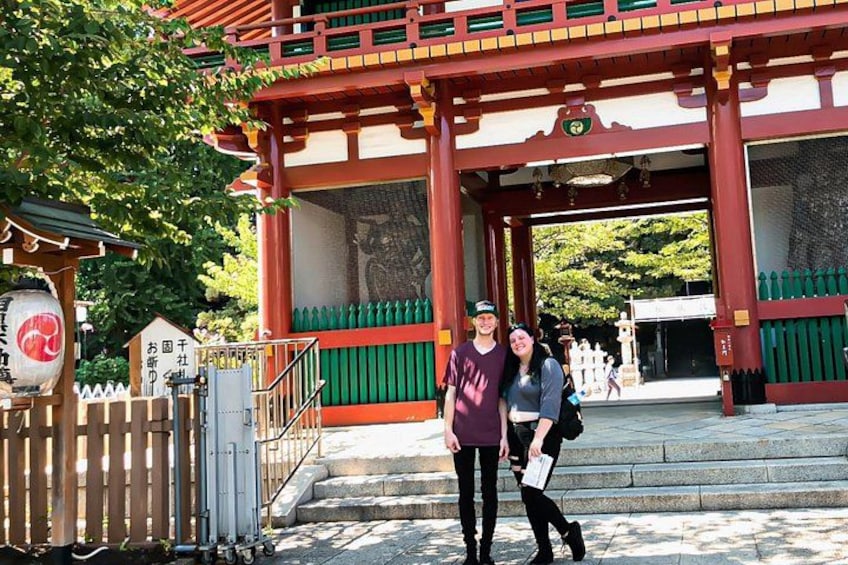 En traditionel japansk port med røde søjler og grønne gelændere, en stentrappe og et lille bedesalon med et skilt. 4