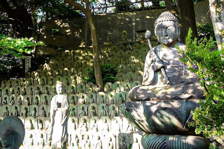 En stor Buddha-statue omgivet af mange mindre statuer i en have. 2