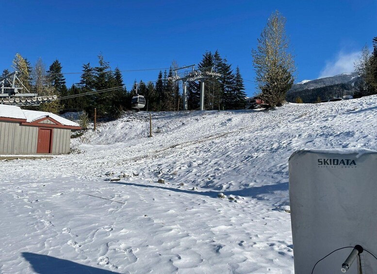 A snowy ski slope with a ski lift, a wooden cabin, and a sign reading 'SKIDATA.' 2