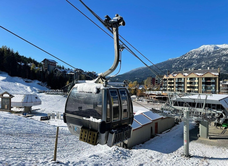 A cable car in a snowy mountainous area with buildings and a clear sky. 1