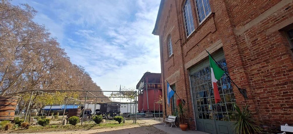 A courtyard with a brick building, a flag, and a tree. 5