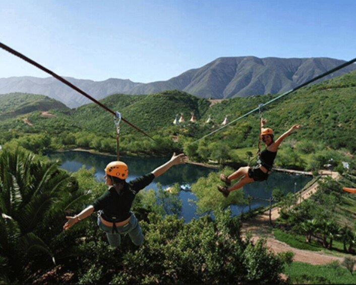 Two people bungee jumping over a river with mountains in the background. 1
