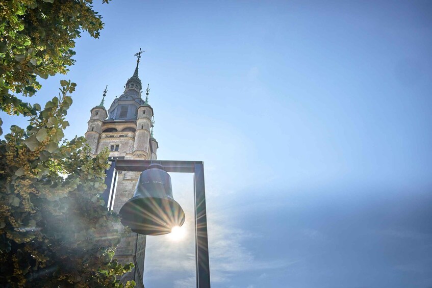 A bell tower with a spire and a bell in the foreground. 4