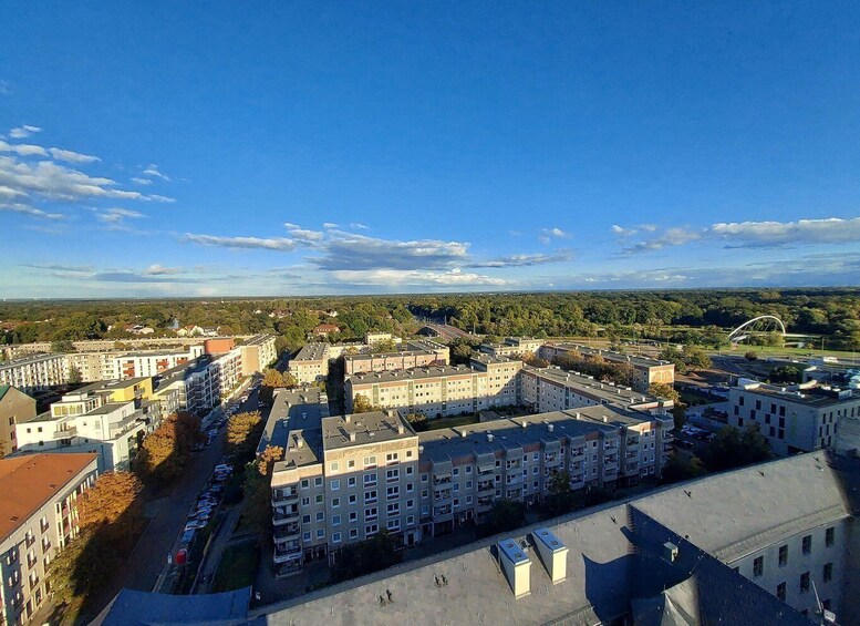 An aerial view of a cityscape with multiple apartment buildings, a clear blue sky, and a distant bridge. 2