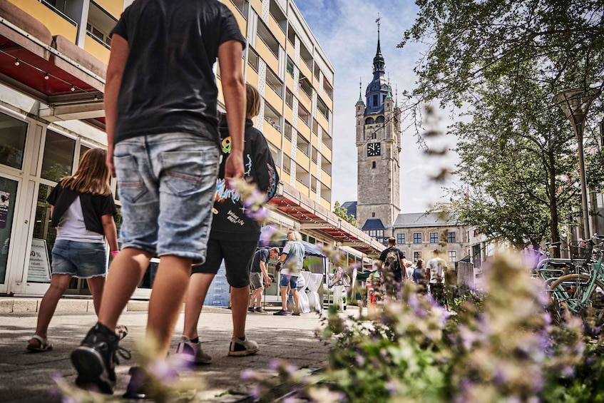 People walking on a city street with a clock tower in the background. 1
