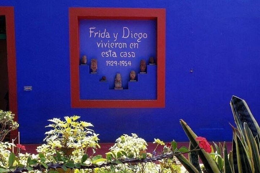 A blue building with a plaque that reads 'Frida y Diego vivieron en esta casa 1929-1954' and a red border. 3