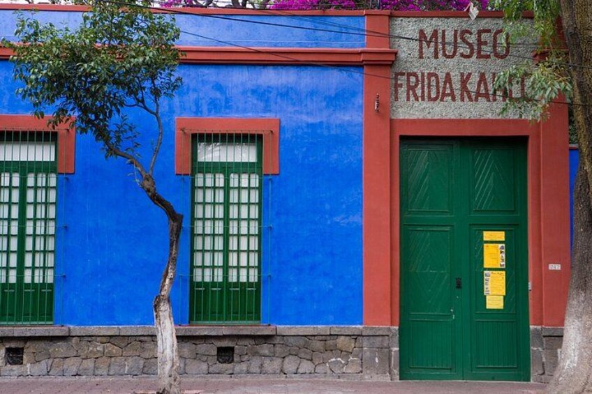 A building with a blue facade, green shutters, and a green door. 1